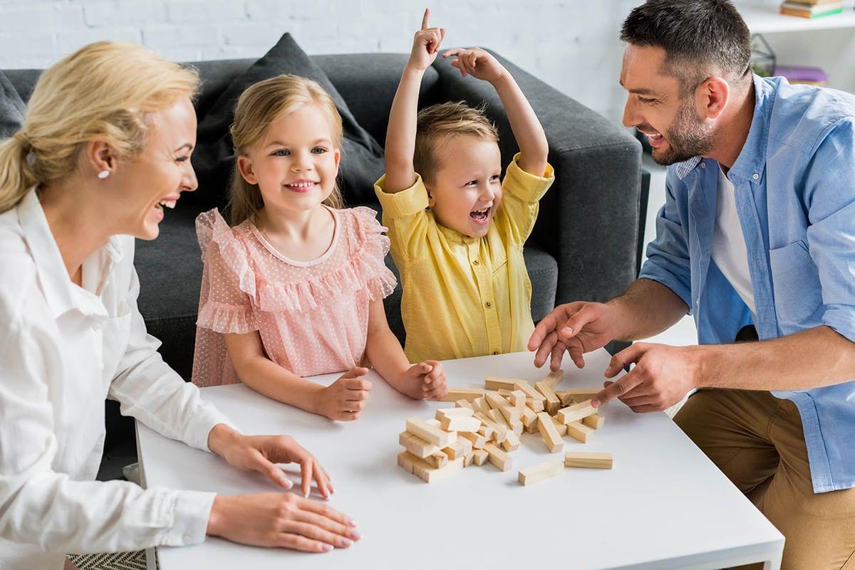 Need for family income benefit in Birmingham shown by a family playing with wooden bricks on a table.