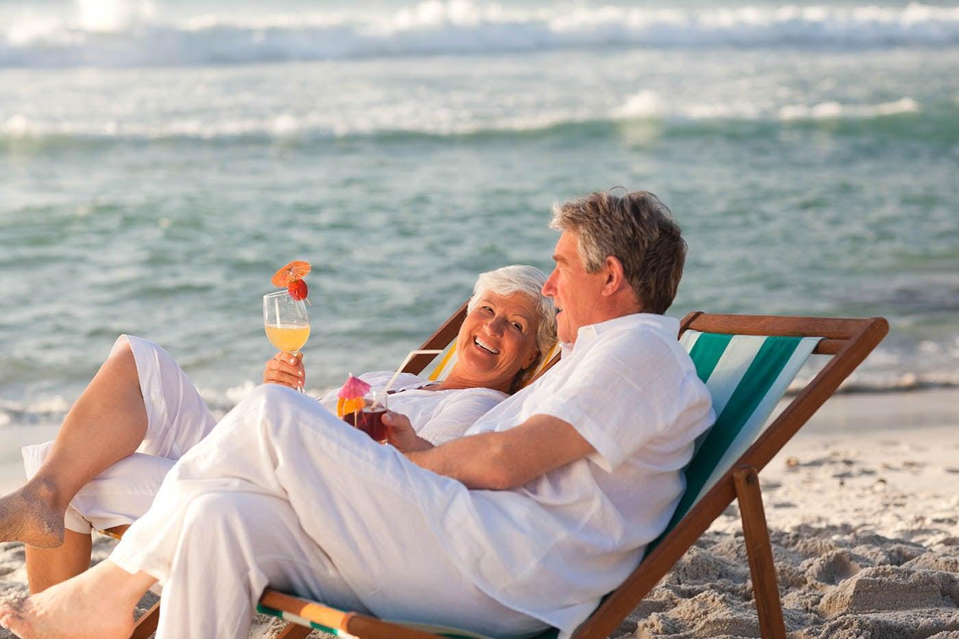 Retired couple sitting in deck chairs drinking cocktails illustrating what you can do with drawdown life time equity release.