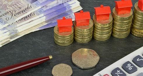 Buy-to-Let Landlords illustrated by toy houses on piles of pound coins.